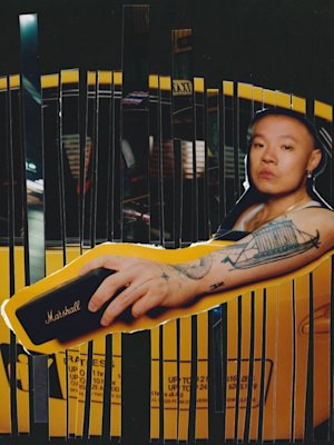Bohan Phoenix holds Marshall Emberton III Black and Brass bluetooth speaker while sitting in the backseat of a yellow taxi.