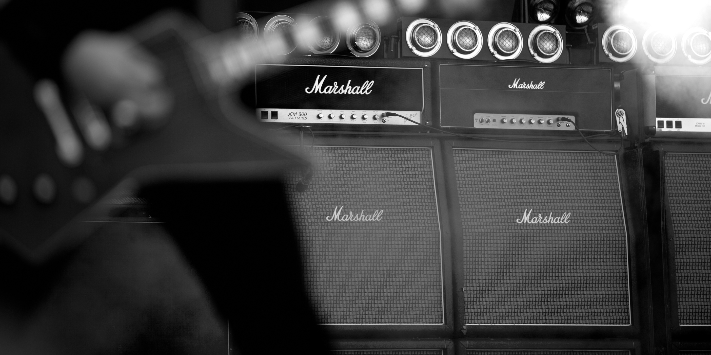 Close-up of a Marshall amplifiers stacked below, blurred guitar in the foreground.