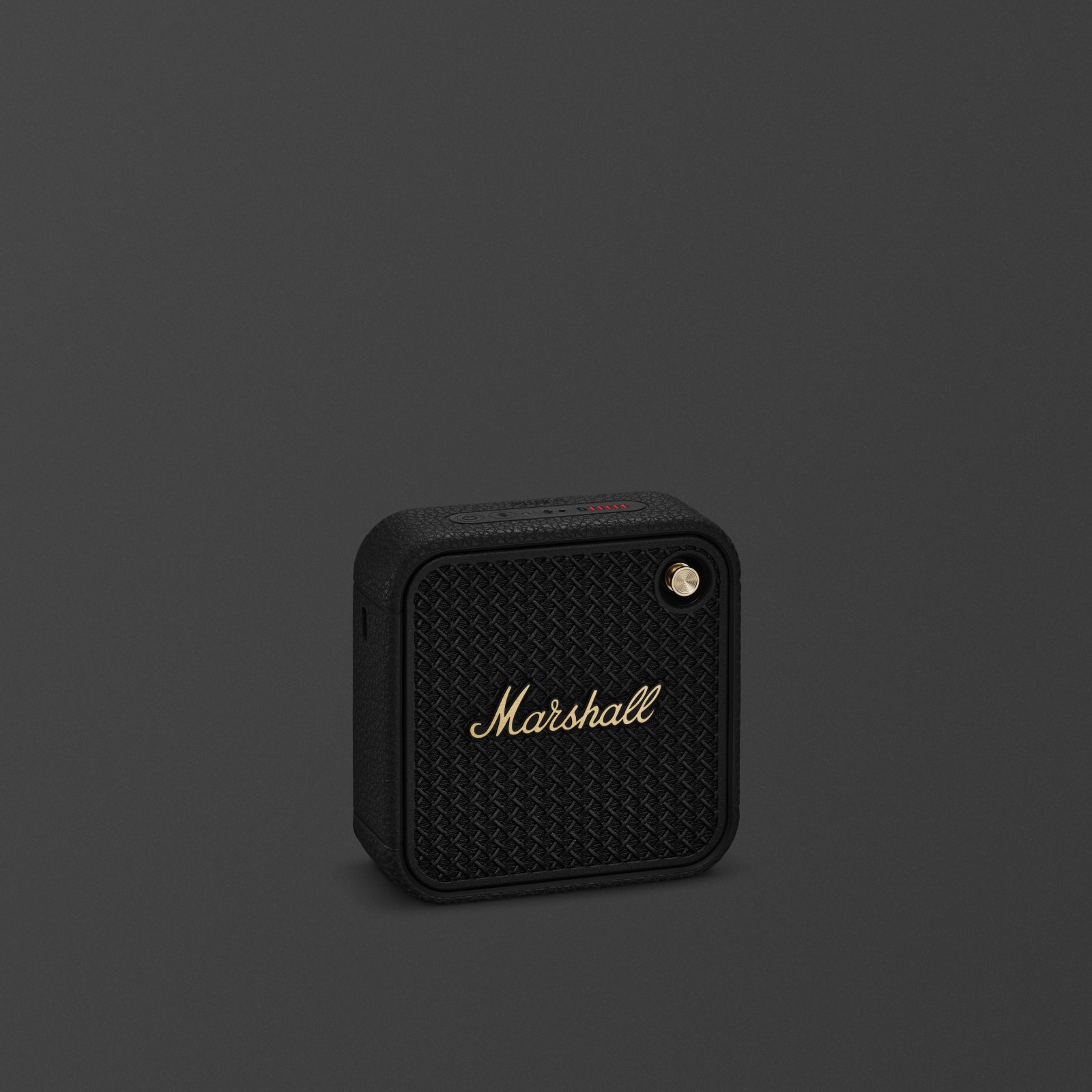 Enceinte bluetooth portable Marshall Willen II noir et laiton sur fond sombre.