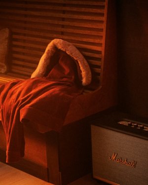 A Refurbished Marshall Speaker placed on the floor, beside the couch of a living room.