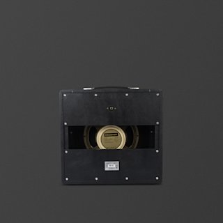 A black Marshall Studio JTM guitar amplifier cabinet viewed from the back, showing an exposed Celestion speaker and a carrying handle on top against a dark background.