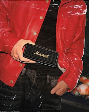 A man wearing a red jacket holding a Marshall speaker.