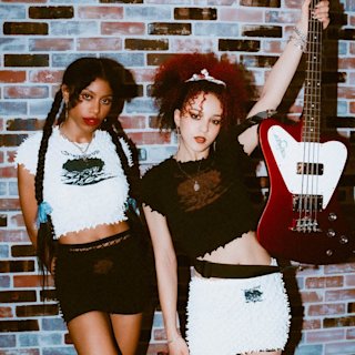 Nova Twins posing in front of a bricked wall