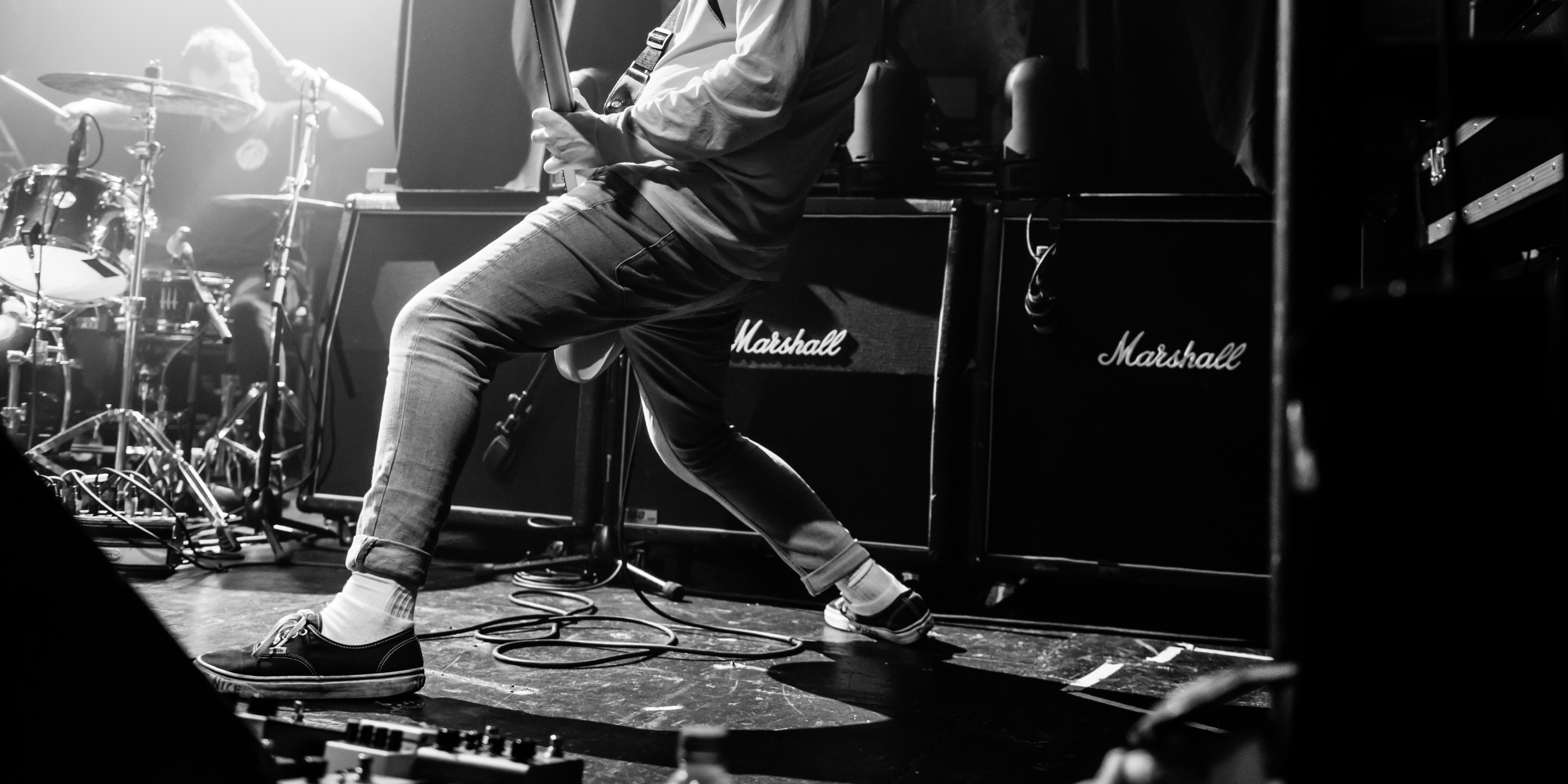 Photo vintage en noir et blanc d'un guitariste jouant de sa guitare devant des amplificateurs Marshall.