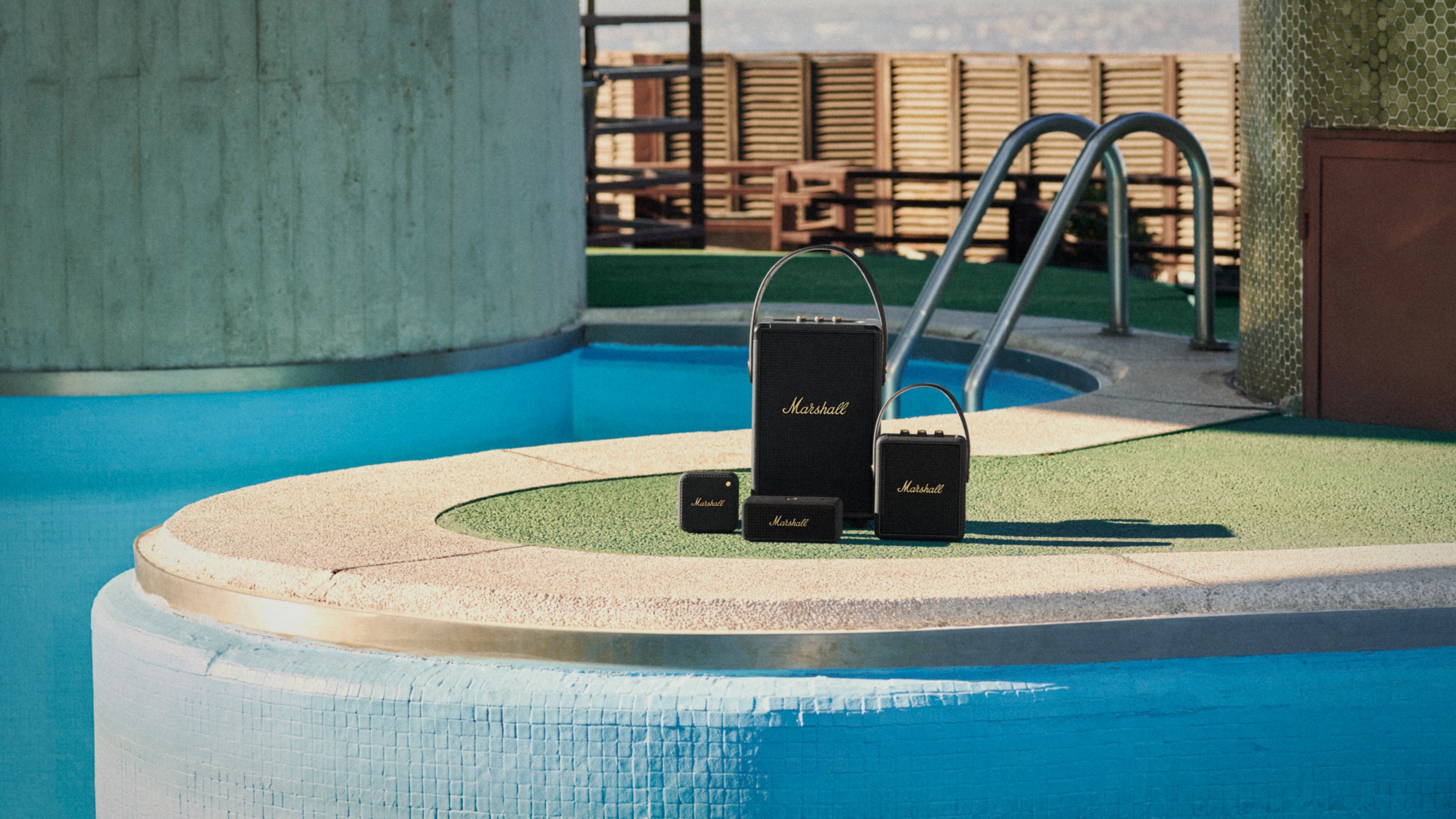 Marshall's black speakers in front of a swimming pool.  