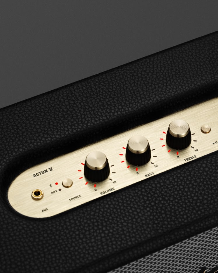 Une photo en gros plan des détails dorés du panneau de contrôle situé sur le dessus d'une enceinte Marshall Acton II Black.