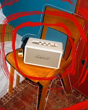 Marshall Kilburn III Cream portable speaker sits on a wooden chair in a room, with digitally added red paint marks on the image.