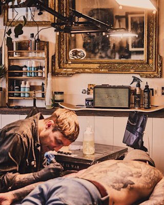 Un tatuador tatúa a su cliente en el Welcome Studio.
