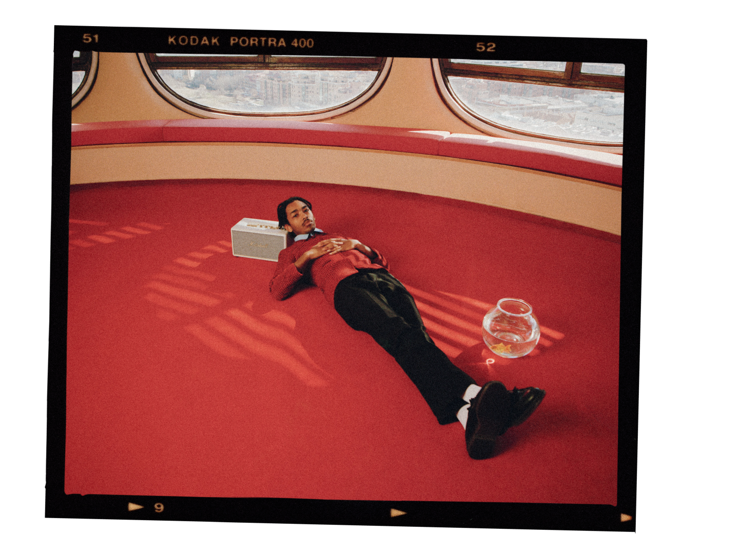 A man laying on a red carpet in a room that is equipped with high-quality Marshall STANMORE III speakers.