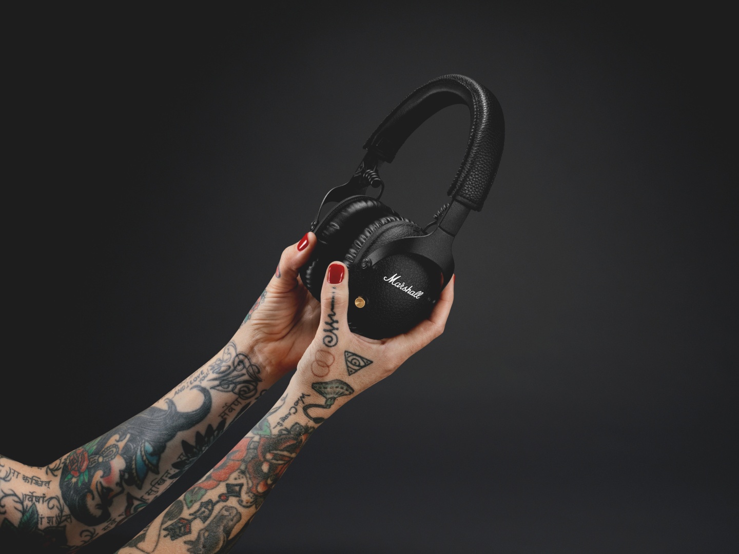 A woman adorned with tattoos rocking a pair of Marshall MONITOR II ANC headphones.
