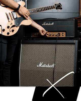 A man is playing a guitar in front of a Marshall JTM45 2245 Head.