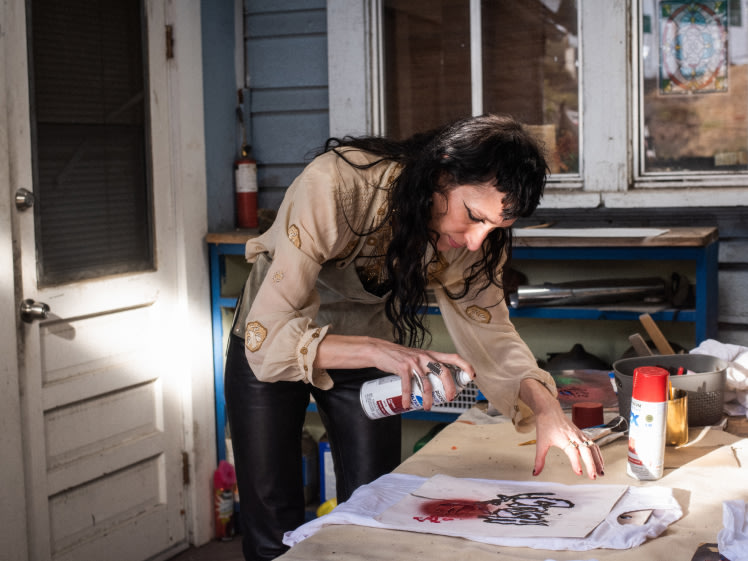 Zumi Rosow is painting a piece of paper on a table.