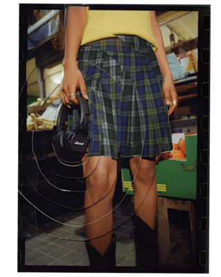 Eine Frau steht auf einem Markt und hält ein Paar Marshall Major V Black On-Ear-Kopfhörer in der Hand.