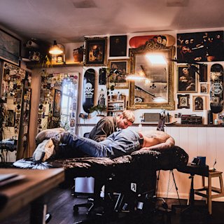 Un hombre se tumba para hacerse un tatuaje en el Welcome Studio