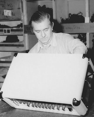 An old photo of a man working on an electronic Marshall COMBO 2525C amplifier.