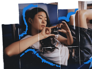 座ってMarshall Minor IV Blackトゥルーワイヤレスイヤホンを手にする女性。