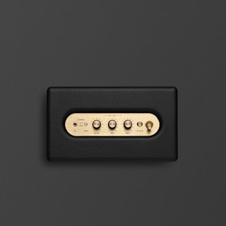 A black Marshall Acton III home speaker with a brass control panel featuring four knobs and a switch, set against a plain dark background.