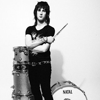 Dhani Mansworth posing next to a stack set of natal snare drums