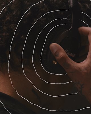 A man is holding a pair of Marshall MONITOR II ANC headphones in front of a circle.