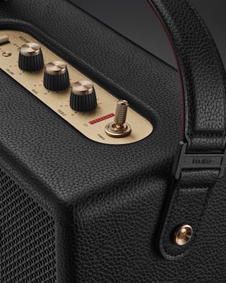 Close-up of the Marshall Kilburn III Black and Brass, featuring a black textured design, metal control knobs, a toggle switch, and a leather handle for easy portability.