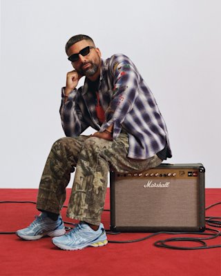 A man sitting on top of a Marshall amplifier.