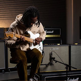 A musician playing guitar using a Marshall Origin50 Combo in a Studio