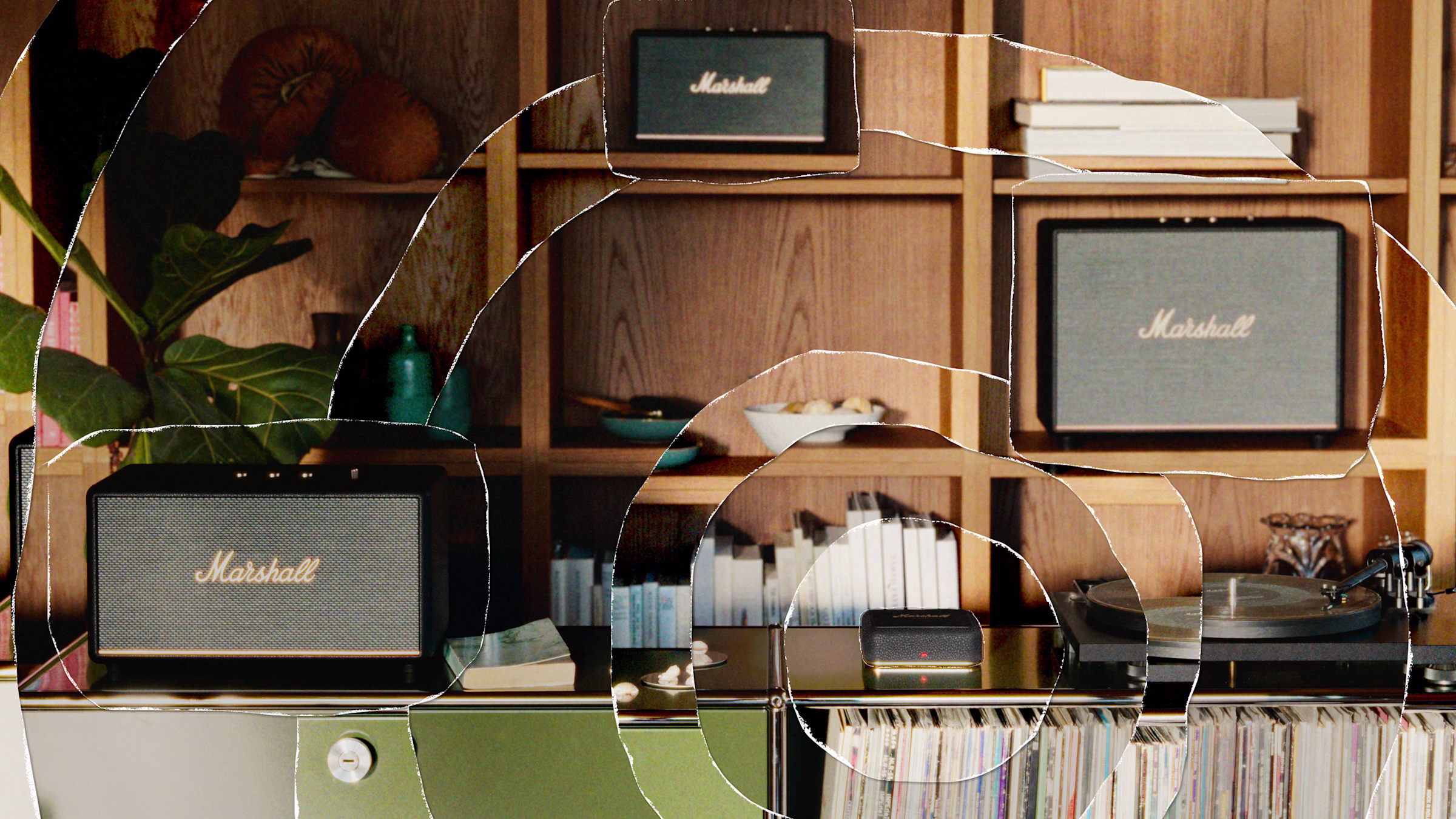 A wooden shelf holds books, bowls, and three Marshall speakers. Below, a green cabinet displays Heddon and a record player.