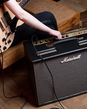 A man studying music whilst connected to a Marshall amplifier.