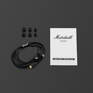 Marshall Mode USB-C headphones, four spare earbud tips, and a user guide arranged on a dark surface.
