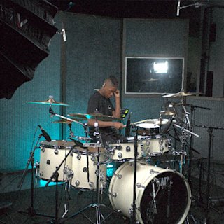 Daniel Letman playing in a studio with a white set of the Natal drums