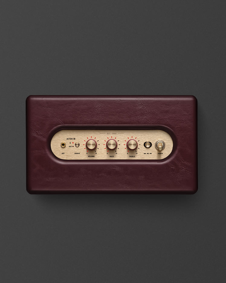 A close-up of a Marshall Acton III Burgundy speaker, showing control knobs and switches on a gold panel.