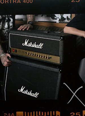 Un homme se tient à côté d'un Marshall JCM900 4100 Head.