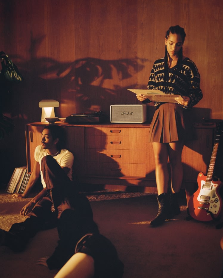 Eine Gruppe von Personen genießt den überwältigenden Klang eines Stanmore III Cream Home-Lautsprechers von Marshall, während sie vor ihm auf dem Boden liegen.