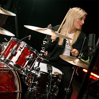 Paige Proctor playing on a red drum by Natal