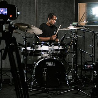 JJ Wallace playing drum in a shiny yellow Natal drum