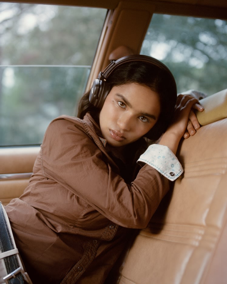 Una mujer con auriculares Marshall Major V Brown se apoya en el asiento de un coche.