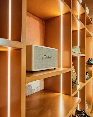 Una estantería en una tienda con zapatos en los compartimentos y una crema Marshall Acton