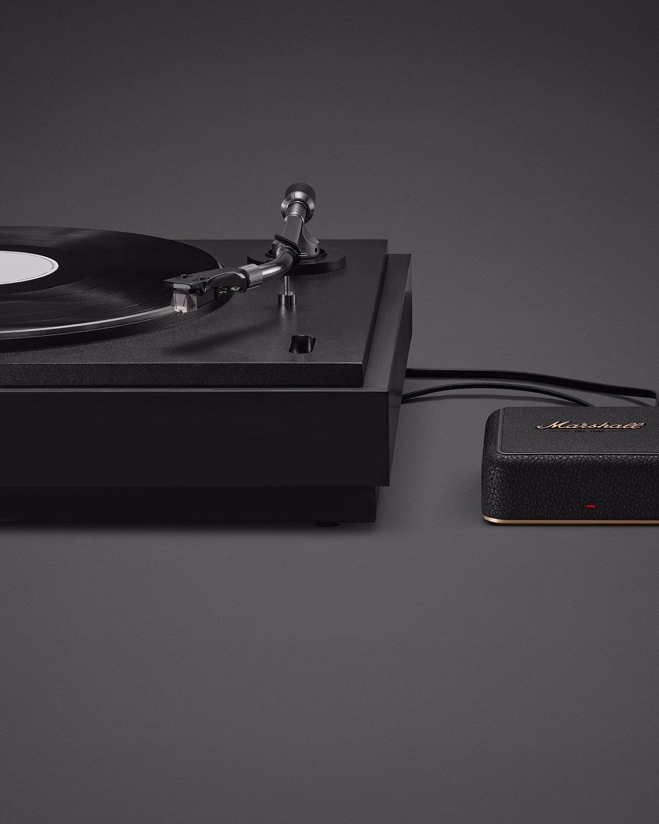 A black turntable playing a vinyl record is connected by a cable to Marshall Heddon.