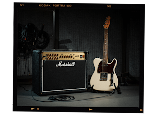 A guitar standing next to the Marshall JVM215 Combo amplifier.