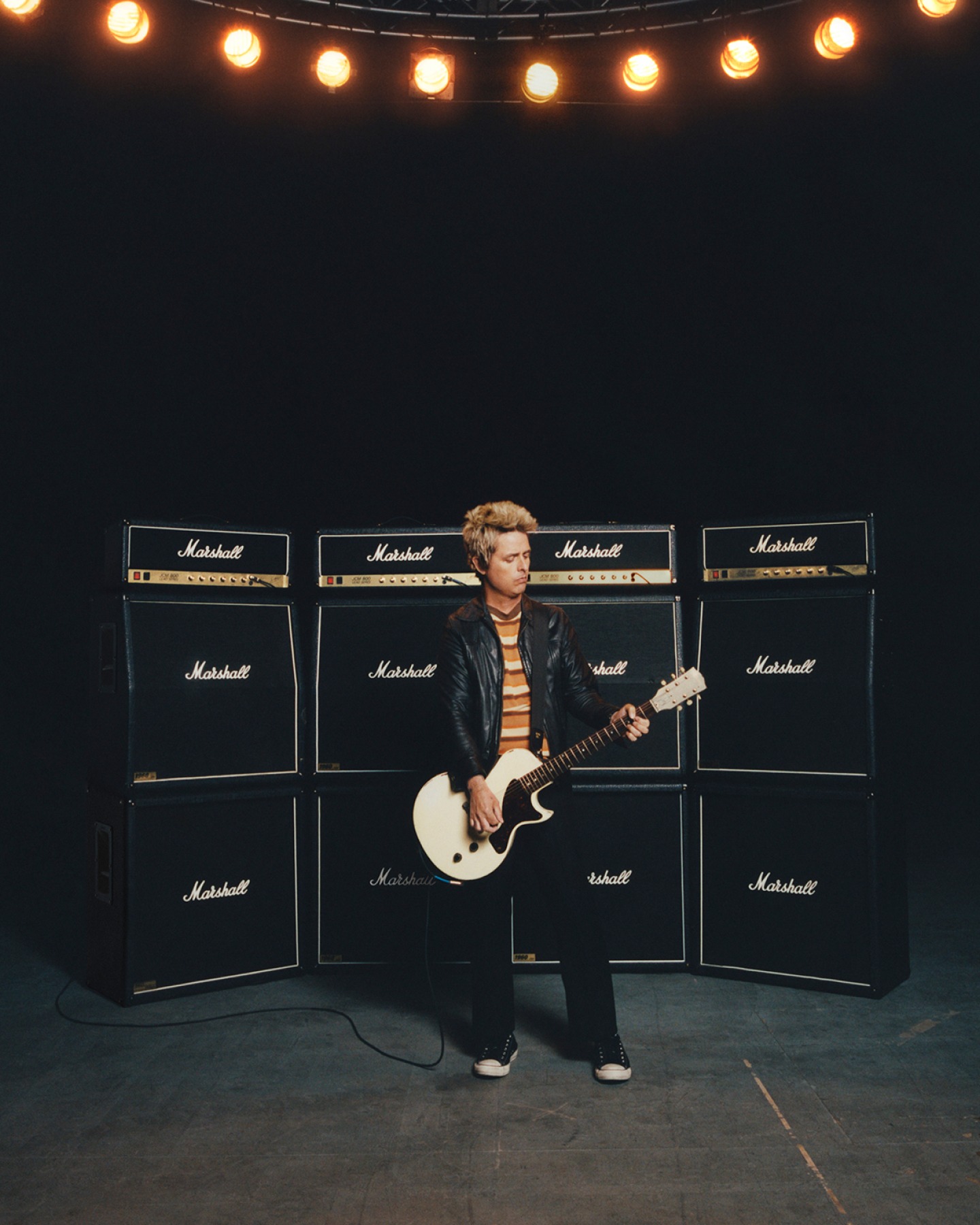 Billie Joe Armstrong playing guitar in front of Marshall amplifiers, cabinets and heads.