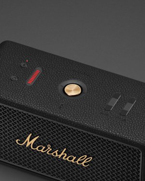 The power button, bluetooth button, control knob and bass and treble controls on top of a black Marshall Middleton II speaker.