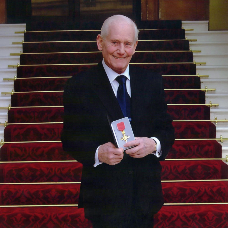 Jim Marshall en la escalinata del Palacio de Buckingham con su OBE