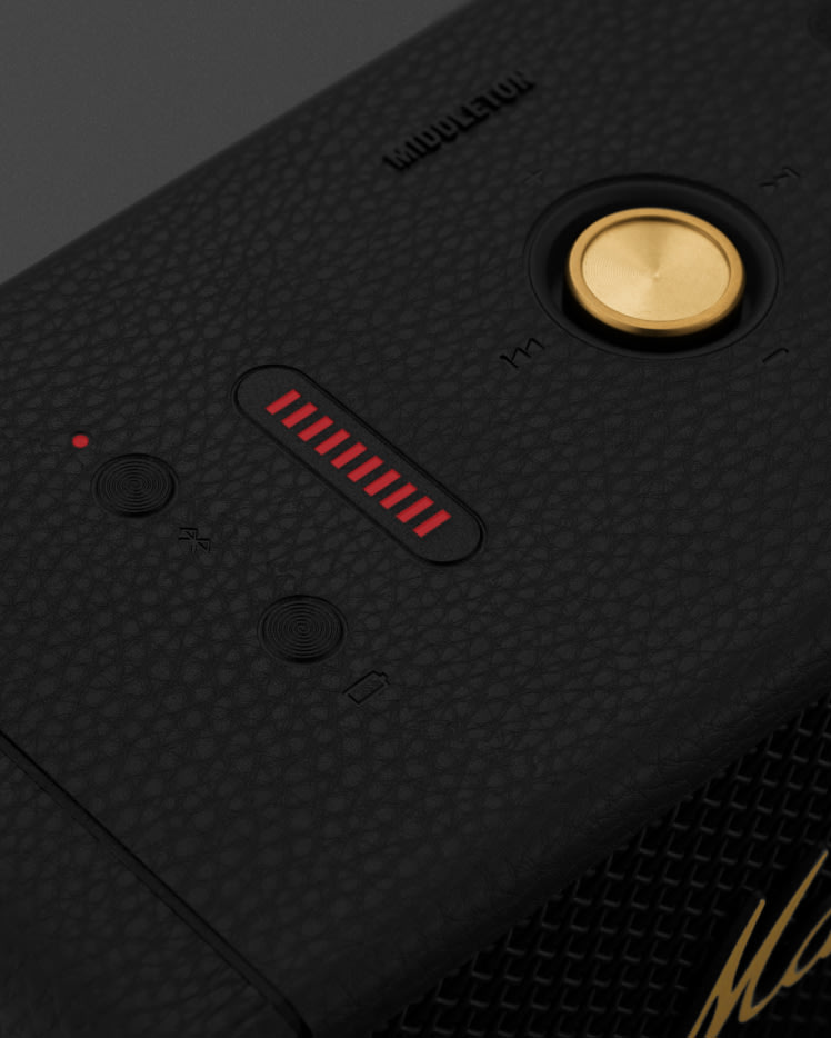 Le dos d'un téléphone Middleton noir et laiton avec un bouton rouge qui sert de haut-parleur portable.