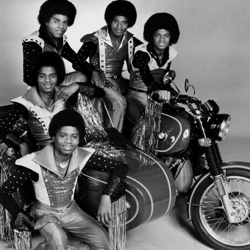 Los Jackson 5 están sentados en trajes a juego en y alrededor de una moto