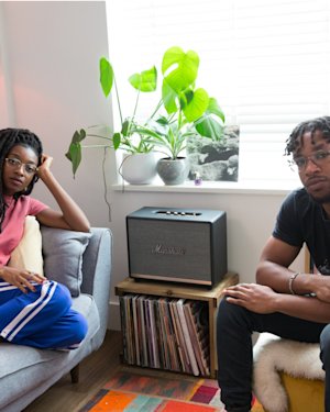 Little Simz and Osiris sitting in a room next to Marshall home speaker.
