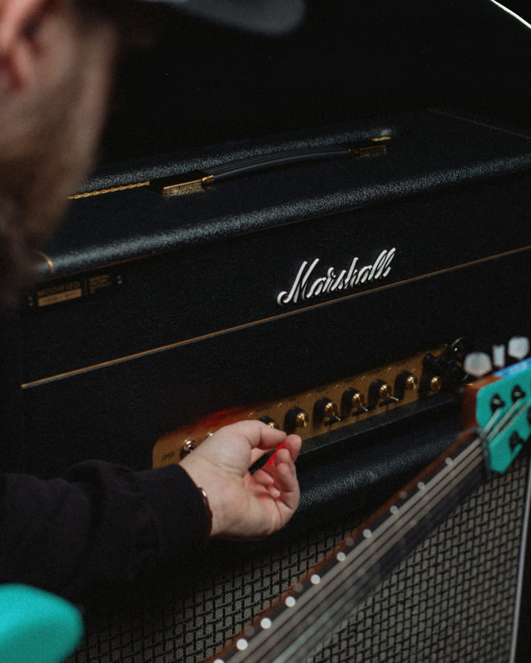 A person adjusting the control knobs in the front of the 1959 Modified amp