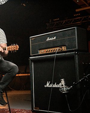 A guitar player wearing a striped t-shirt playing connected to the 1959 Modified amplifier