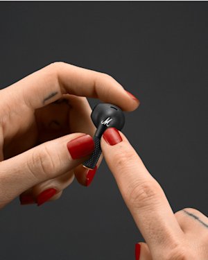 Hand with red painted nails holding a Minor III earbud.