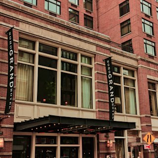 Außenansicht des historischen Grand Hotels mit klassischer Backsteinfassade, großen Fenstern und einer schwarzen Markise.