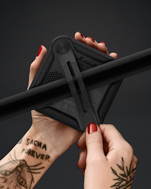 A hand with tattoos using the fastening strap to attach a Willen speaker to a rail.